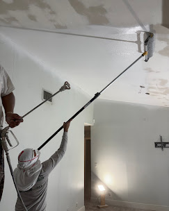 Two-man crew spraying joint compound for level 5 ceiling finish